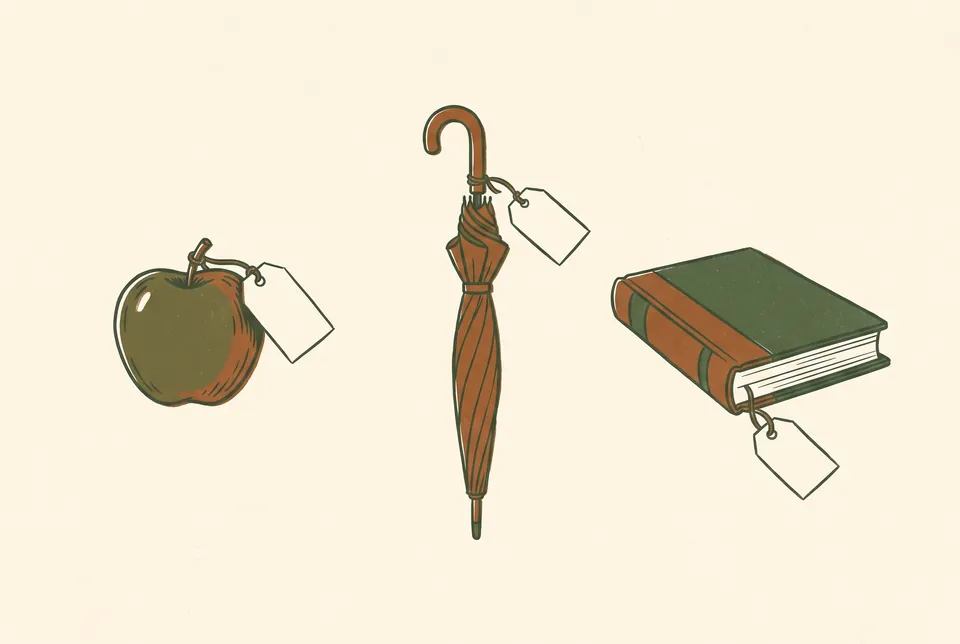An apple, a closed umbrella and a book, each with a small blank paper tag on a string.